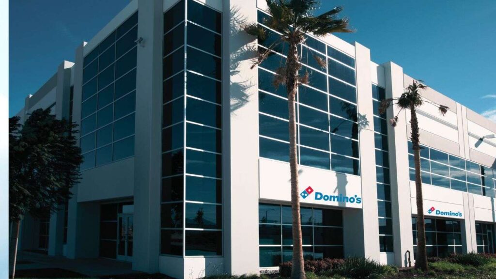 Dominos Headoffice, a white building with palm trees in front.